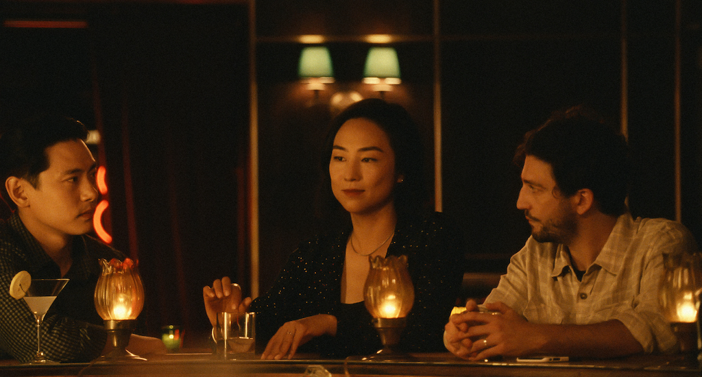 Characters played by Teo Yoo, Greta Lee, and John Magaro sitting in a bar